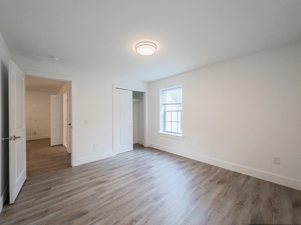 A room with a window and a wooden floor.