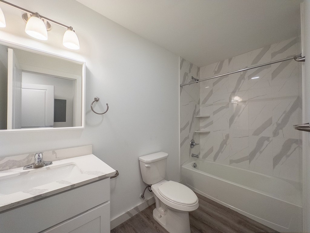 A white bathroom with a toilet, sink, and shower.