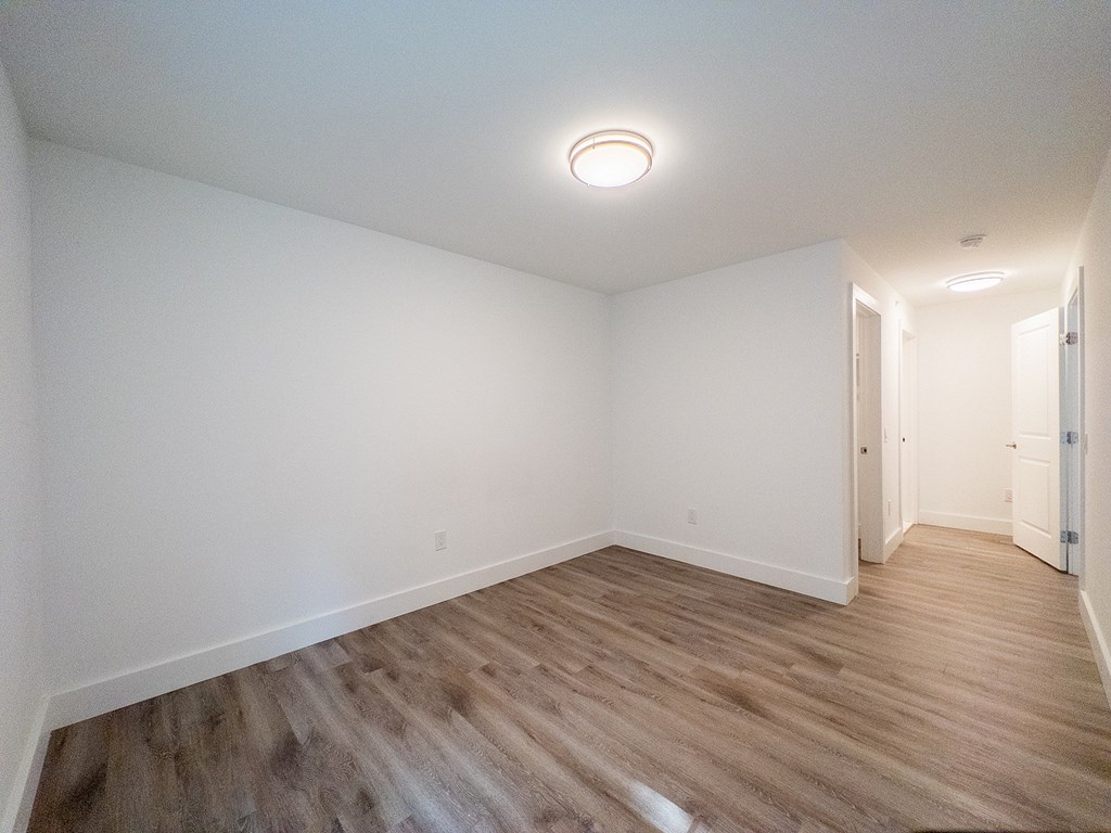 A room with wooden flooring and white walls.