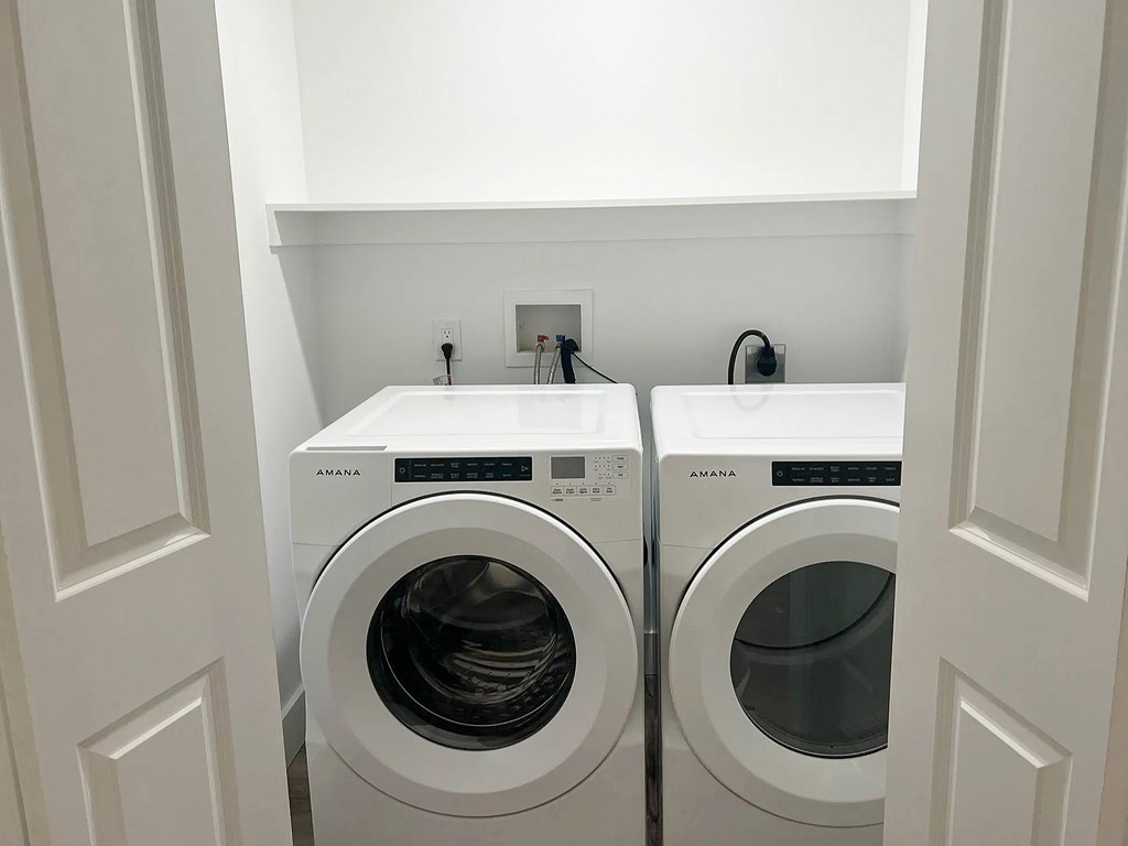 Two white front loading washing machines in a laundry room.