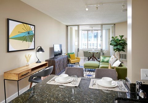 A modern living room with a black granite countertop and a large abstract painting on the wall.