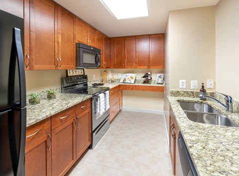 A kitchen with brown cabinets and black appliances.
