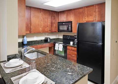 A kitchen with black appliances and brown cabinets.