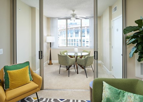 A living room with a yellow chair and a green chair with a table and chairs in the background.