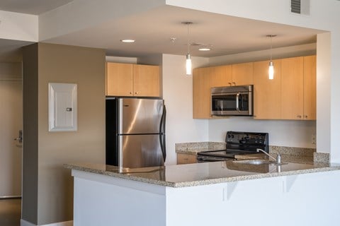 A modern kitchen with a stainless steel refrigerator and microwave above the stove.