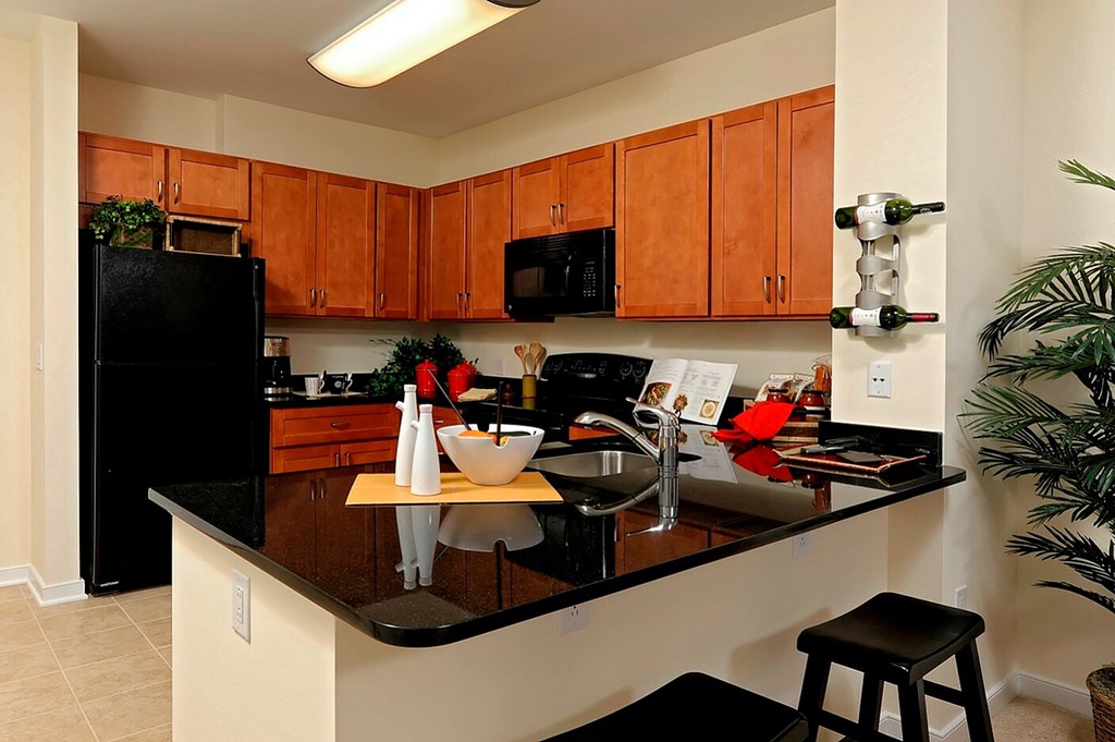 A kitchen with black appliances and brown cabinets.