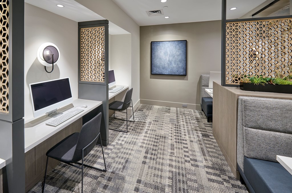 A room with a desk, chairs, and a painting on the wall.