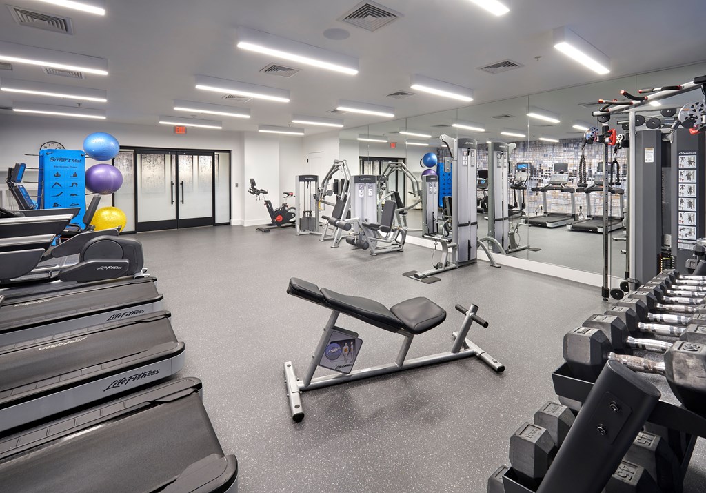 A gym with a variety of equipment including treadmills, weights, and exercise machines.