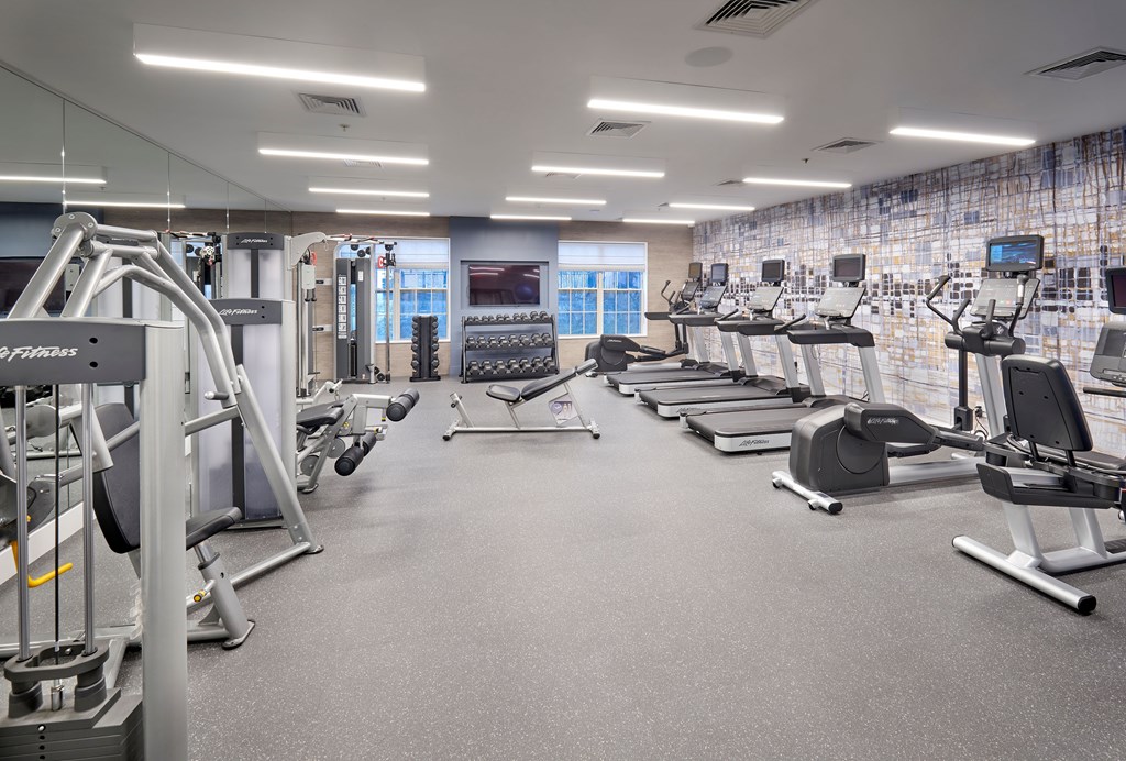 A spacious gym with various exercise machines and a tiled wall.