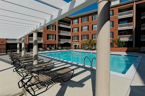 A pool with chairs and a building in the background.