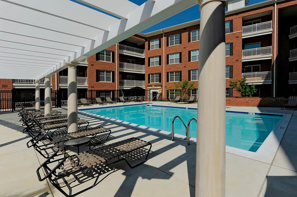 A pool with chairs and a building in the background.
