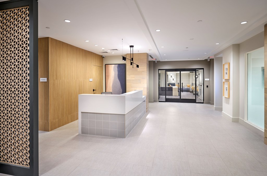A reception area with a white counter and a patterned wallpaper.