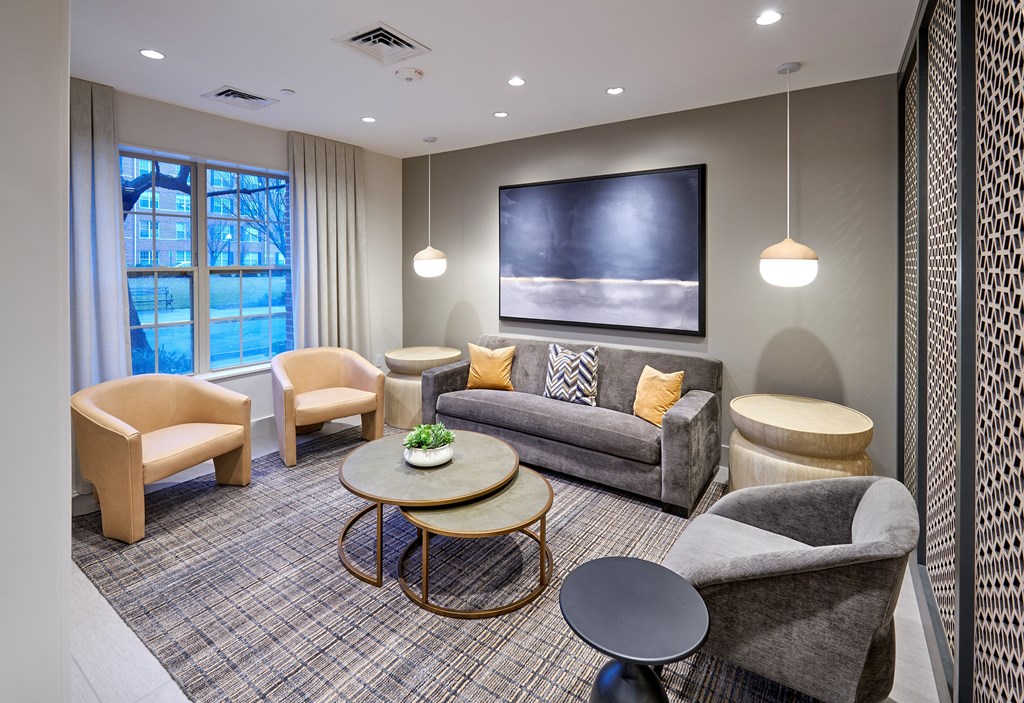 A living room with a grey couch, a coffee table, and a large window.