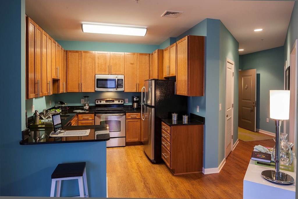 A kitchen with wooden cabinets and a black refrigerator.