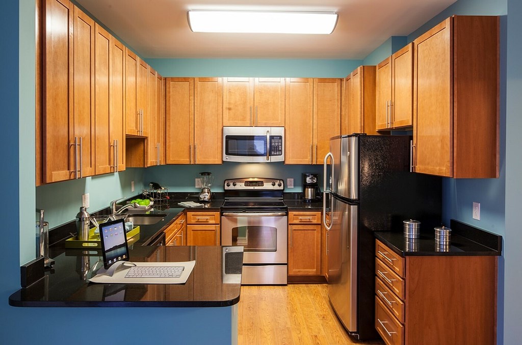 A kitchen with wooden cabinets and black countertops.