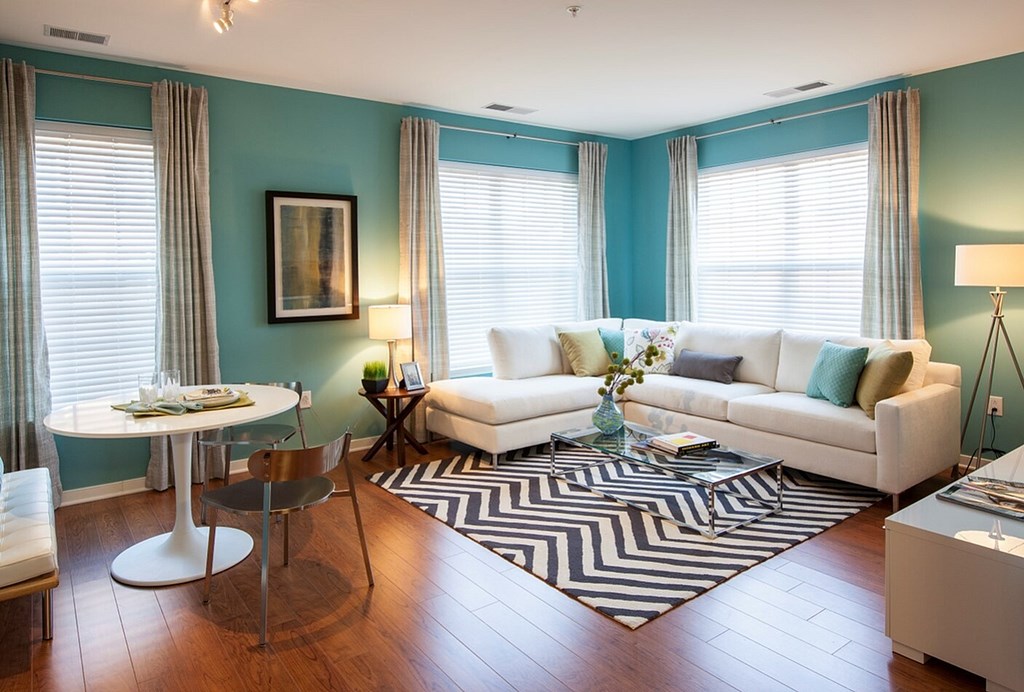 A living room with a white couch, a round table, and a painting on the wall.