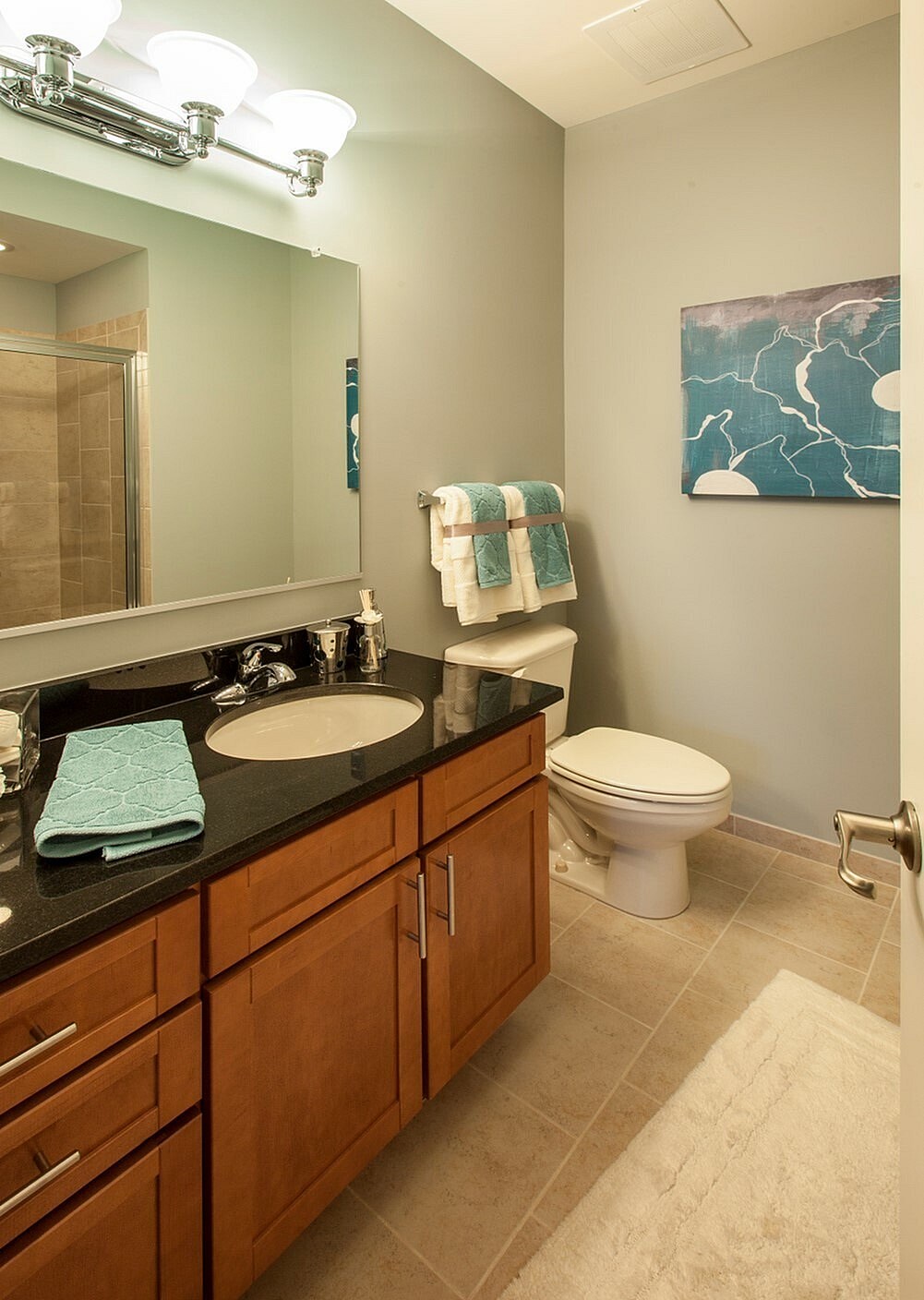 A bathroom with a toilet, sink, and mirror.