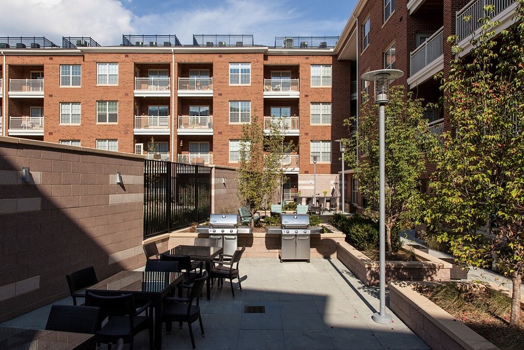 A patio with tables and chairs is surrounded by a brick building.