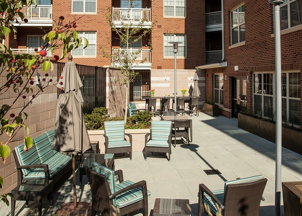 A patio with chairs and umbrellas in front of a brick building.