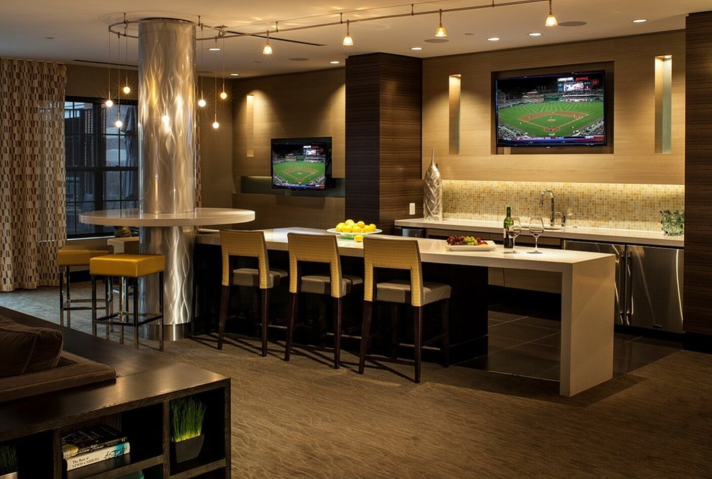 A modern bar area with a television screen showing a baseball game.
