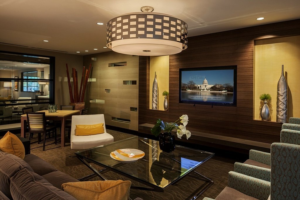 A modern living room with a glass coffee table and a large painting on the wall.