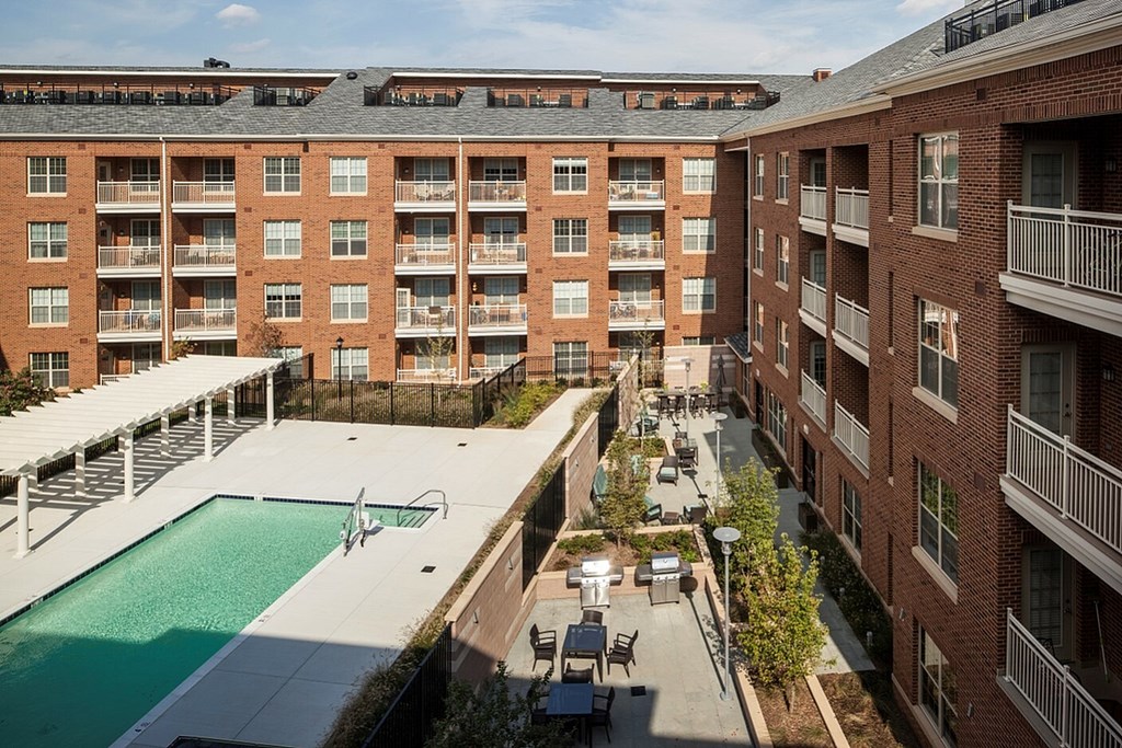 A view of a pool and patio area of a red brick apartment complex.