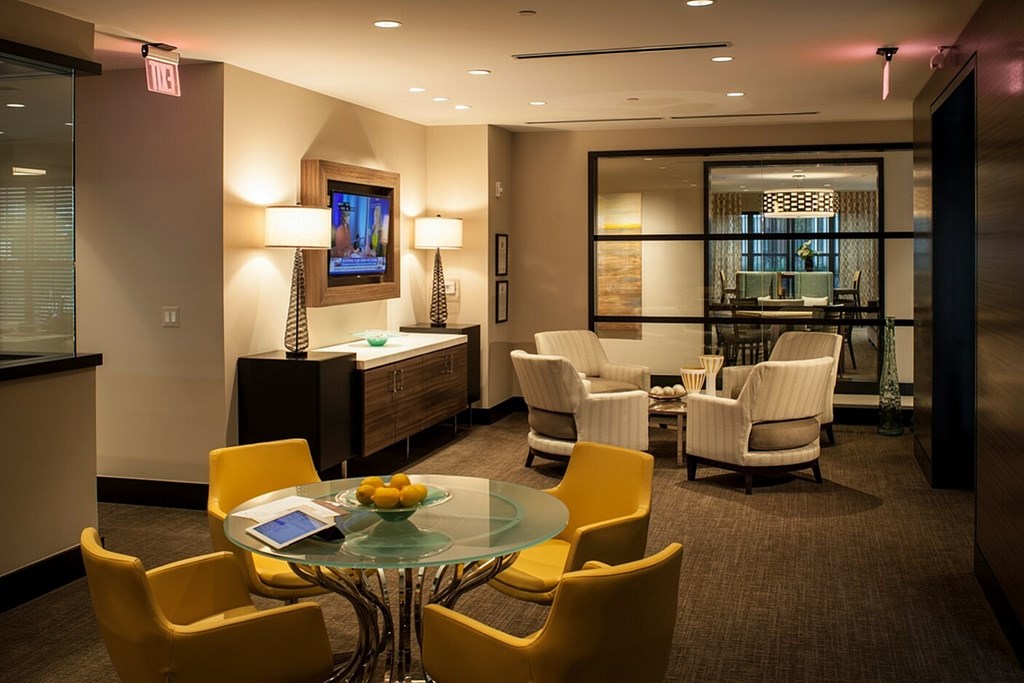 A conference room with a glass table surrounded by yellow chairs.