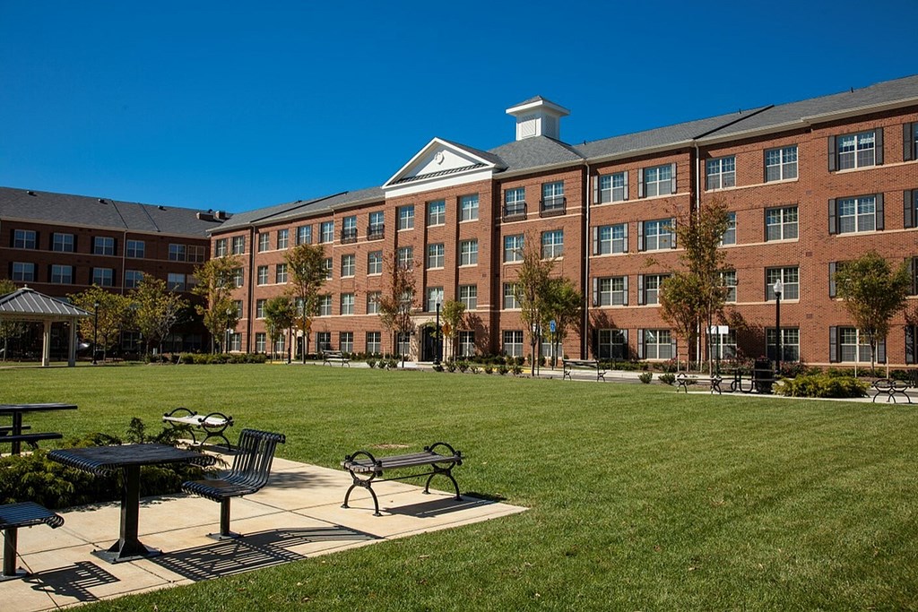 A large red brick building with a white tower and a green lawn in front.