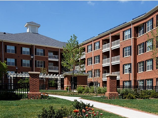 A red brick building with a white roof and a black fence.