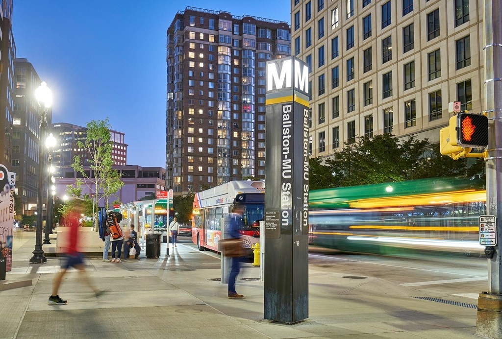 A busy city street at dusk with a bus and pedestrians.
