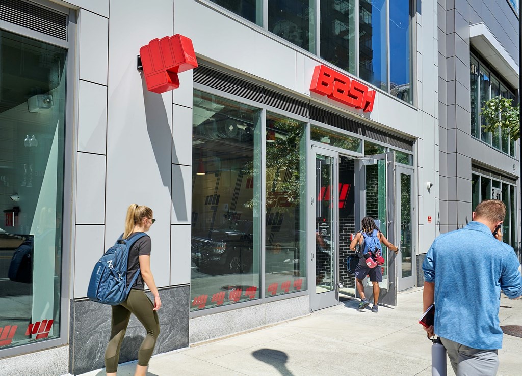 A woman with a blue backpack is walking past a Bose store.