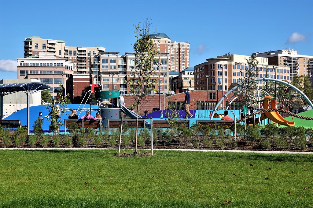 A playground with a slide and swings in front of apartment buildings.