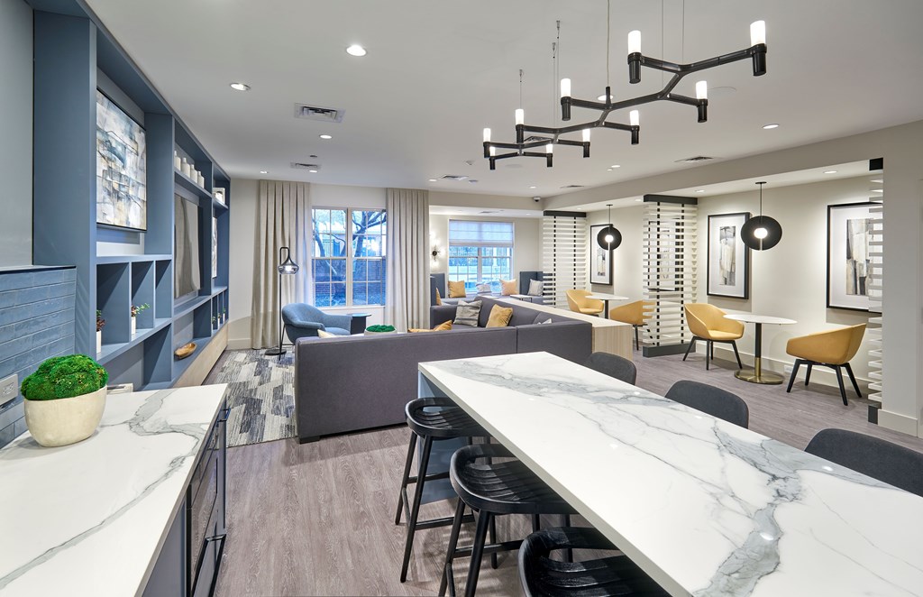 A modern kitchen with a marble countertop and a dining area with chairs and a table.