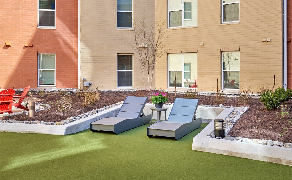A small garden with a lawn and a few chairs.