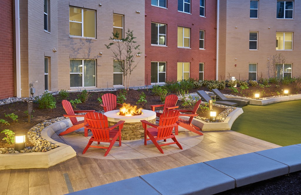 A fire pit surrounded by chairs in a courtyard.