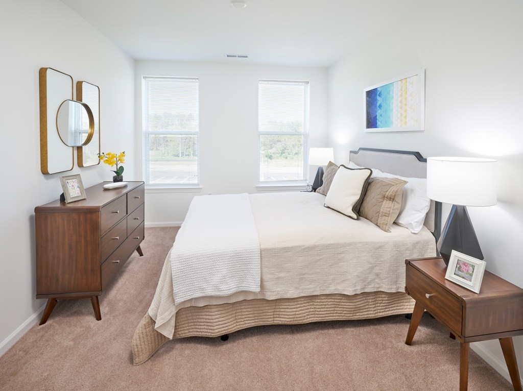 A bedroom with a bed, nightstand, and a dresser with a mirror.