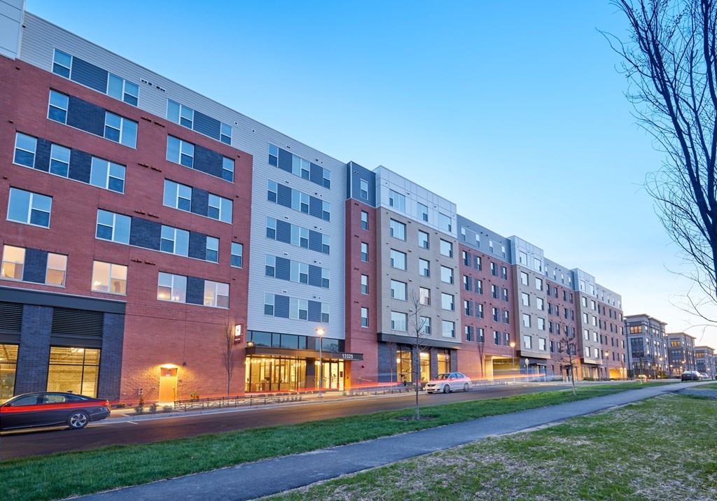 A row of modern apartment buildings with cars parked in front.