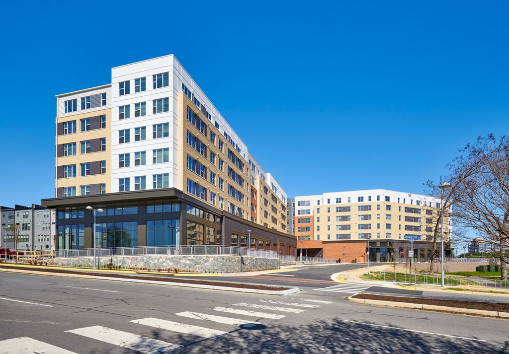 A modern multi-story building with a glass facade is situated in a well-maintained urban area.