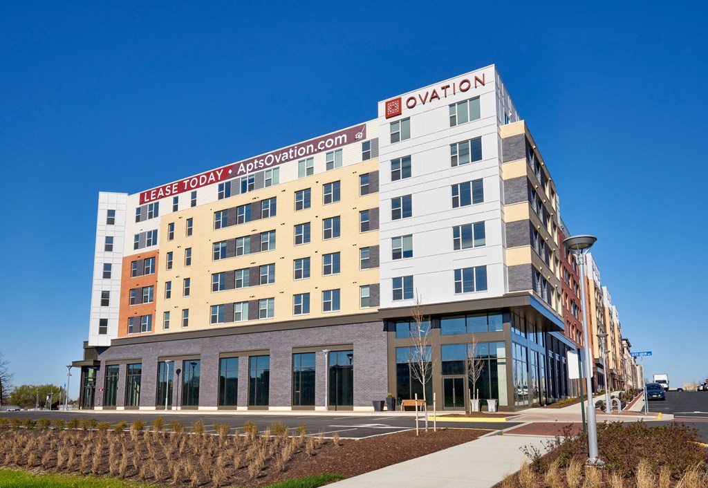 A modern multi-story building with the name "Ovation" on the top floor.
