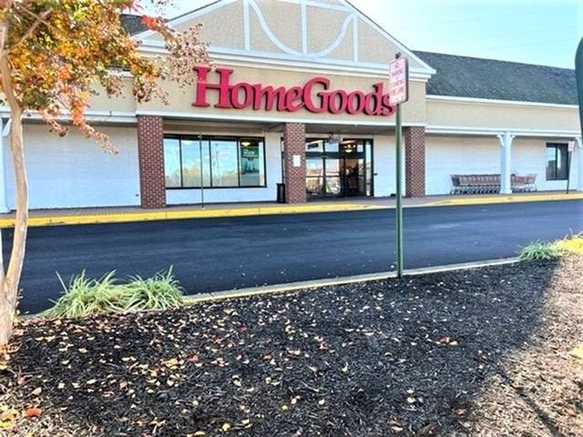 A HomeGoods storefront with a red sign and a bench outside.