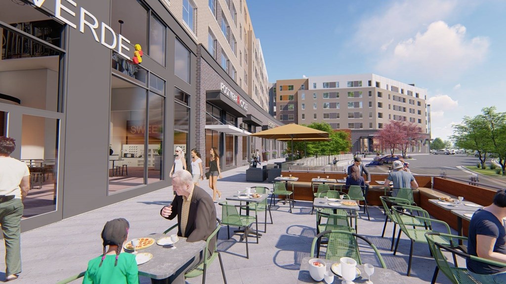 A group of people are sitting at tables outside of a building with a sign that says "VERDE".
