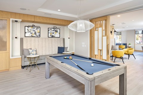 A pool table is in the middle of a room with a chair and a couch.