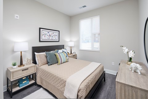 A bedroom with a large bed and a nightstand with a lamp.
