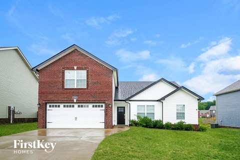 A house with a red brick exterior and a white garage door is shown.