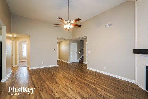 A spacious room with wooden floors and a ceiling fan.