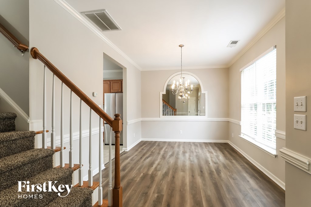 A spacious room with wooden floors and a staircase leading to the upper level.
