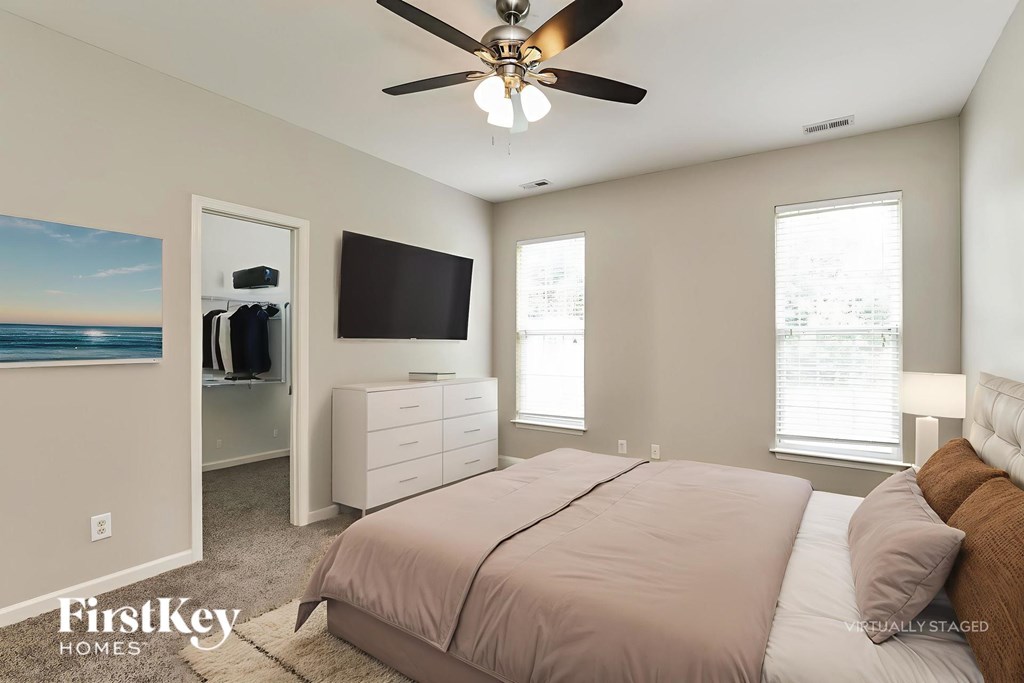 A bedroom with a bed, dresser, and ceiling fan.