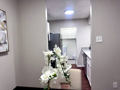 A white framed picture hangs on a white wall above a white sofa.