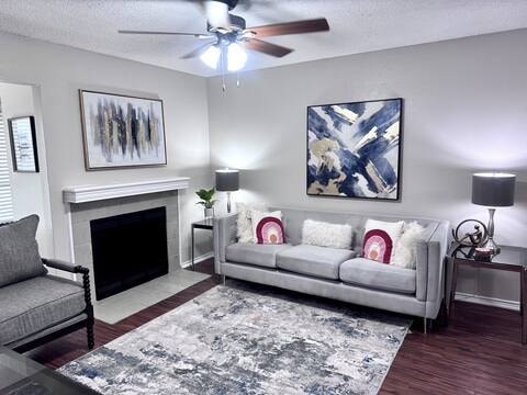 A living room with a grey couch, a fireplace, and a painting on the wall.
