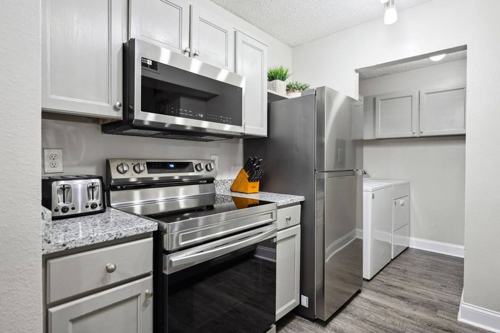A kitchen with a stainless steel refrigerator, oven, and microwave.